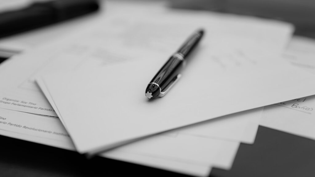 A laptop screen showing a half-finished paragraph beside a notebook covered in handwritten marginalia and arrows.