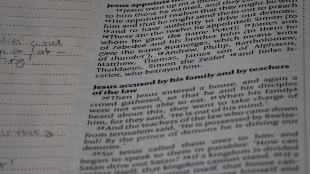 A student's desk scattered with a half-read textbook, a notebook covered in arrows and diagrams, and a single lamp casting focused light.