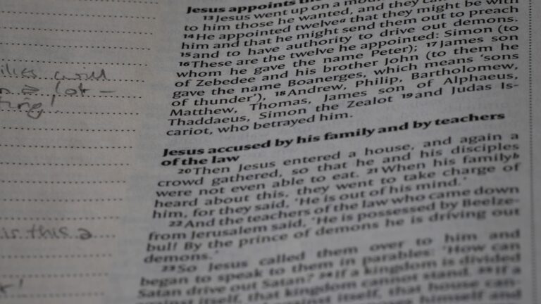 A student's desk scattered with a half-read textbook, a notebook covered in arrows and diagrams, and a single lamp casting focused light.