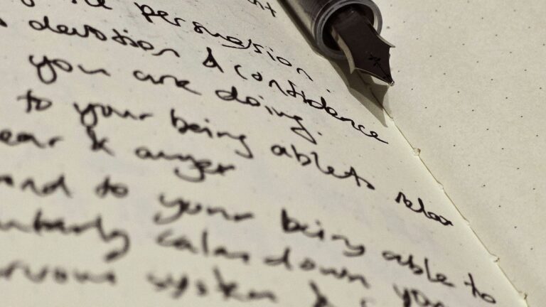 A student at a desk with several open textbooks, a page of handwritten notes, and crossed-out scribbles under focused desk light.
