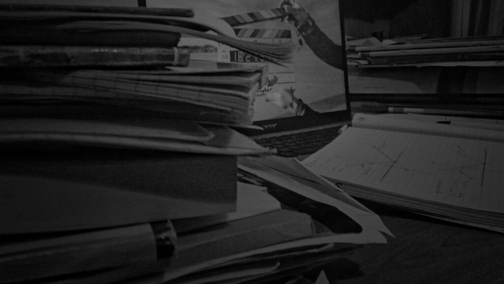A laptop screen shows a university lecture paused mid-slide on a kitchen table beside a half-finished cup of coffee and a notebook.