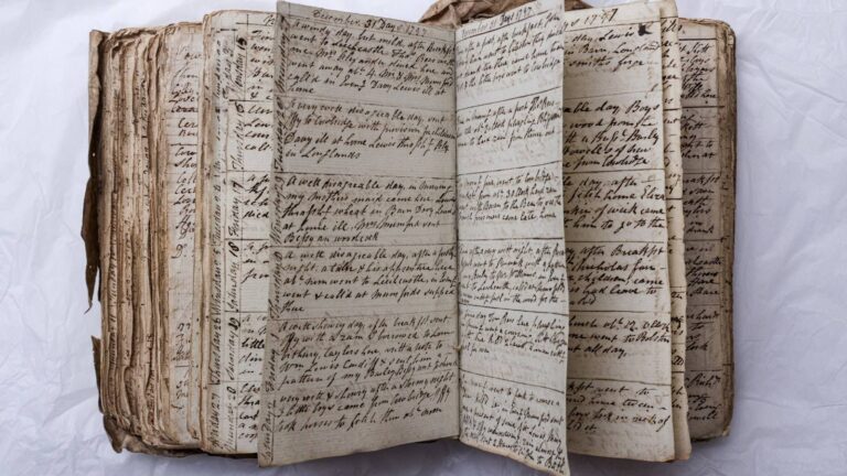 A stack of worn flashcards scattered on a wooden desk next to an open notebook and a cup of black coffee.